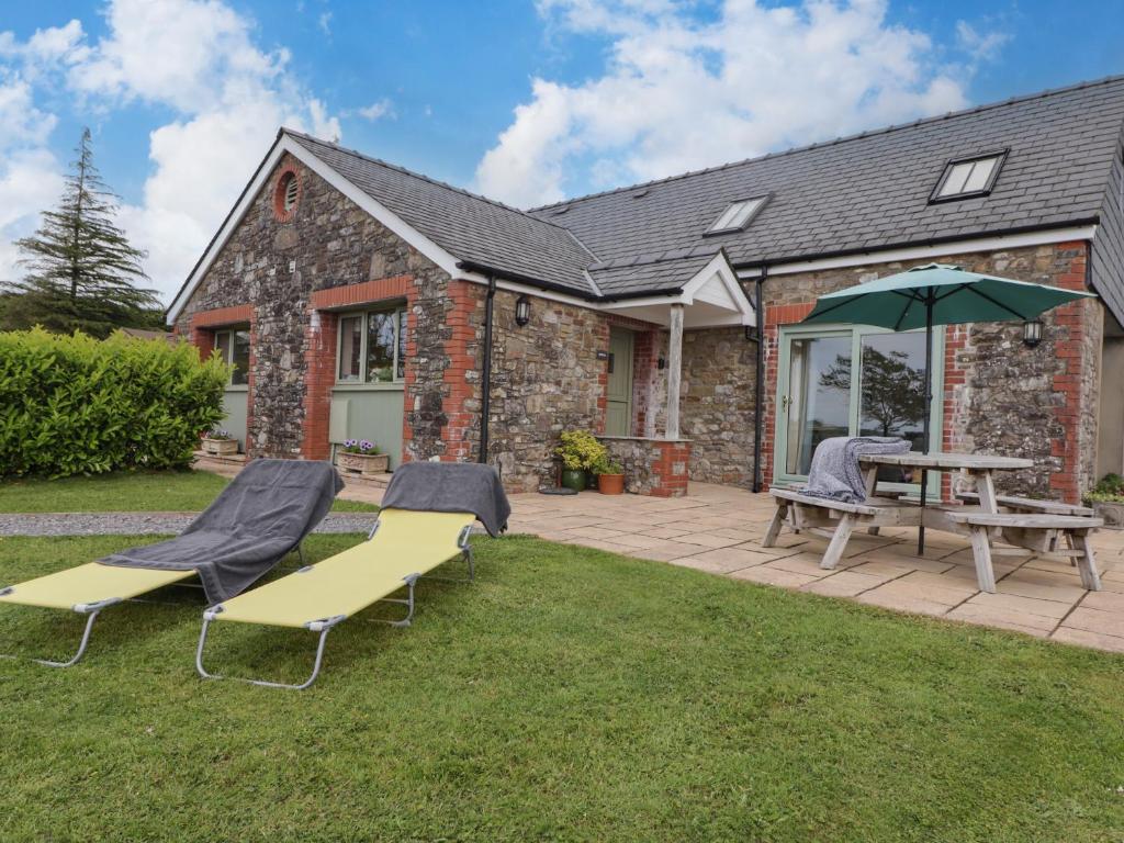 a patio with a table and chairs and an umbrella at Gwennol Cottage in Carmarthen