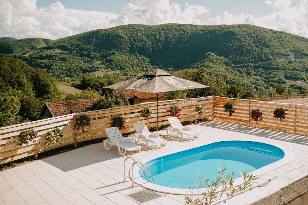 einen Pool mit Stühlen und einem Sonnenschirm auf einer Terrasse in der Unterkunft Vidovo Domacinstvo in Banja Luka