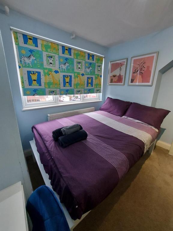 a bedroom with a bed with purple sheets and a window at Large 4 bedrooms golders green in London