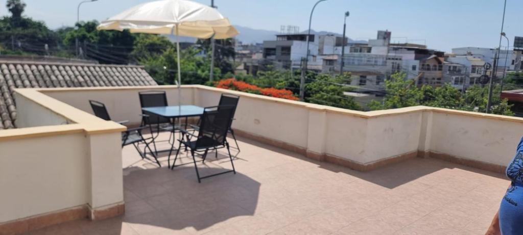 balcón con mesa, sillas y sombrilla en Apart Hotel Cabral, en Lima