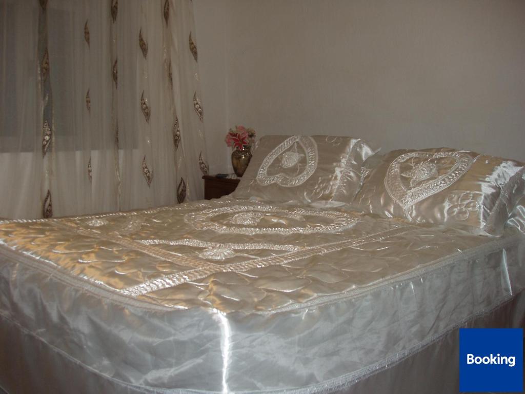 a bed with white sheets and pillows on it at Friendly Hostel in Gjirokastër