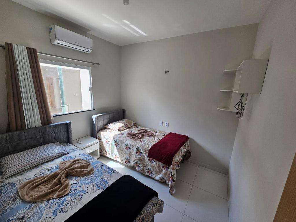 Una pequeña habitación con dos camas y una ventana. en Lençóis Confort - Apartamento, en Barreirinhas