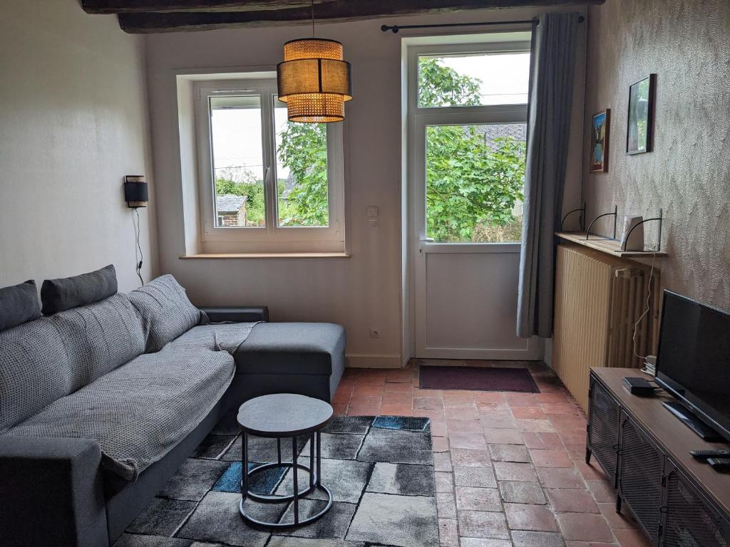 a living room with a couch and a tv at Gîte charmant proche des Châteaux de la Loire avec jardin privatif et parking. - FR-1-410-426 in Chahaignes