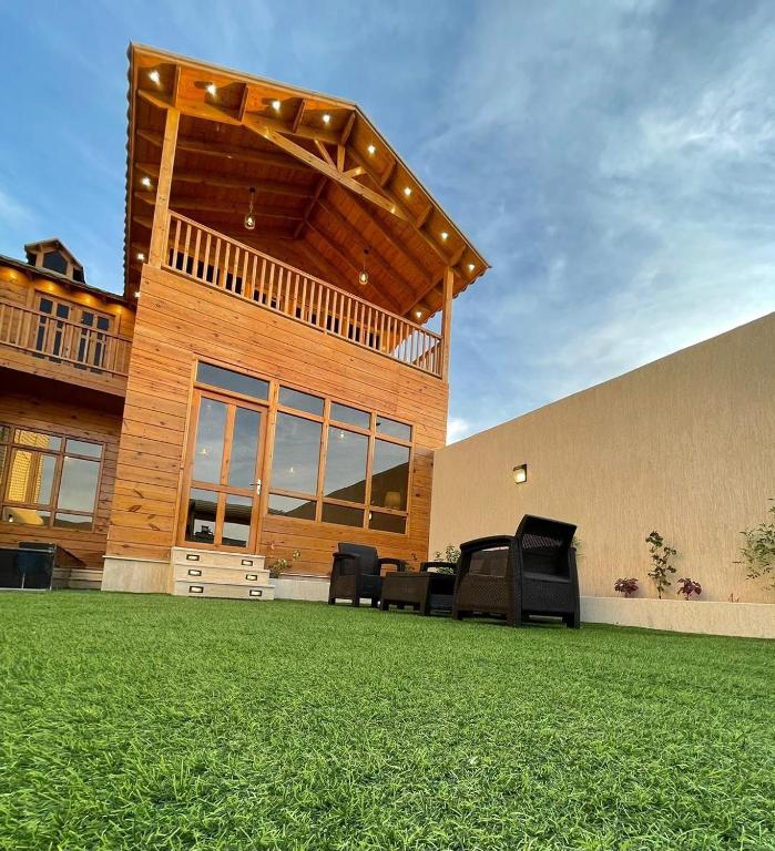 a house with a patio with chairs on a lawn at اكواخ وشاليهات لوزان الريفية in Dahaban