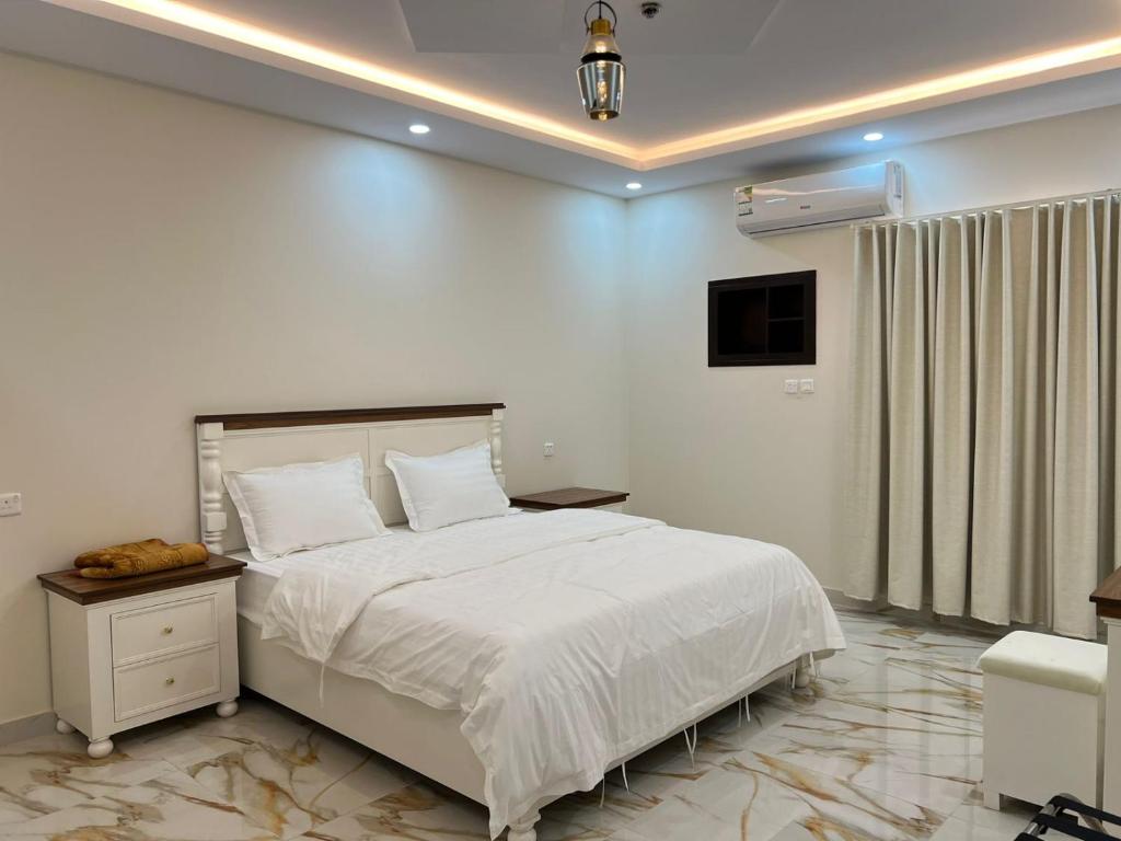 ein weißes Schlafzimmer mit einem Bett und einem TV in der Unterkunft شقق سطام المخدومة in Al Fayşalīyah