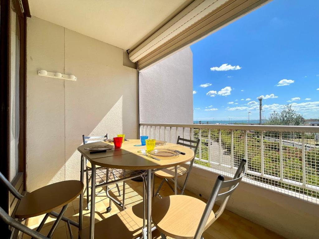 un balcon avec une table et des chaises et une grande fenêtre dans l'établissement Studio cabine lumineux avec parking privé, face à la plage – Sète - FR-1-338-561, à Sète