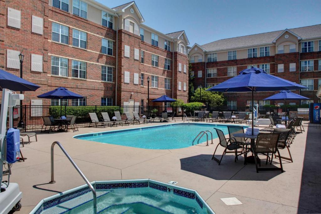 a pool with chairs and tables and a building at Residence Inn by Marriott Cleveland Beachwood in Beachwood