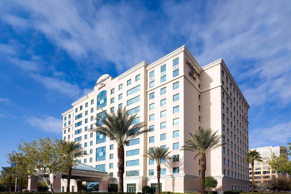 a large white building with palm trees in front of it at Residence Inn by Marriott Las Vegas Hughes Center in Las Vegas