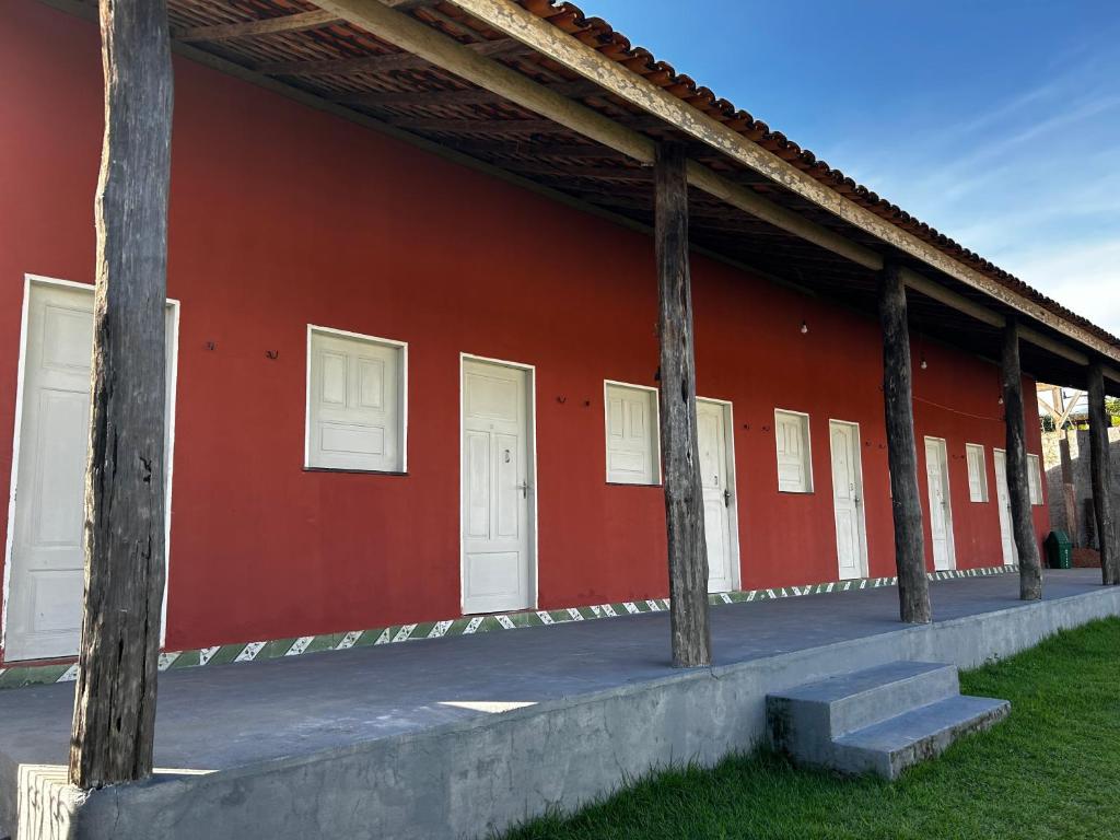 a red building with white doors and some grass at Vila alegria in Salinópolis