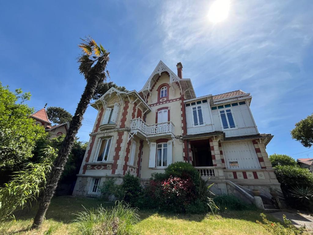une vieille maison avec un palmier en face dans l'établissement Appartement T3 Lumineux - Parking Privé - Proche Centre et Plages d'Arcachon - FR-1-319-567, à Arcachon