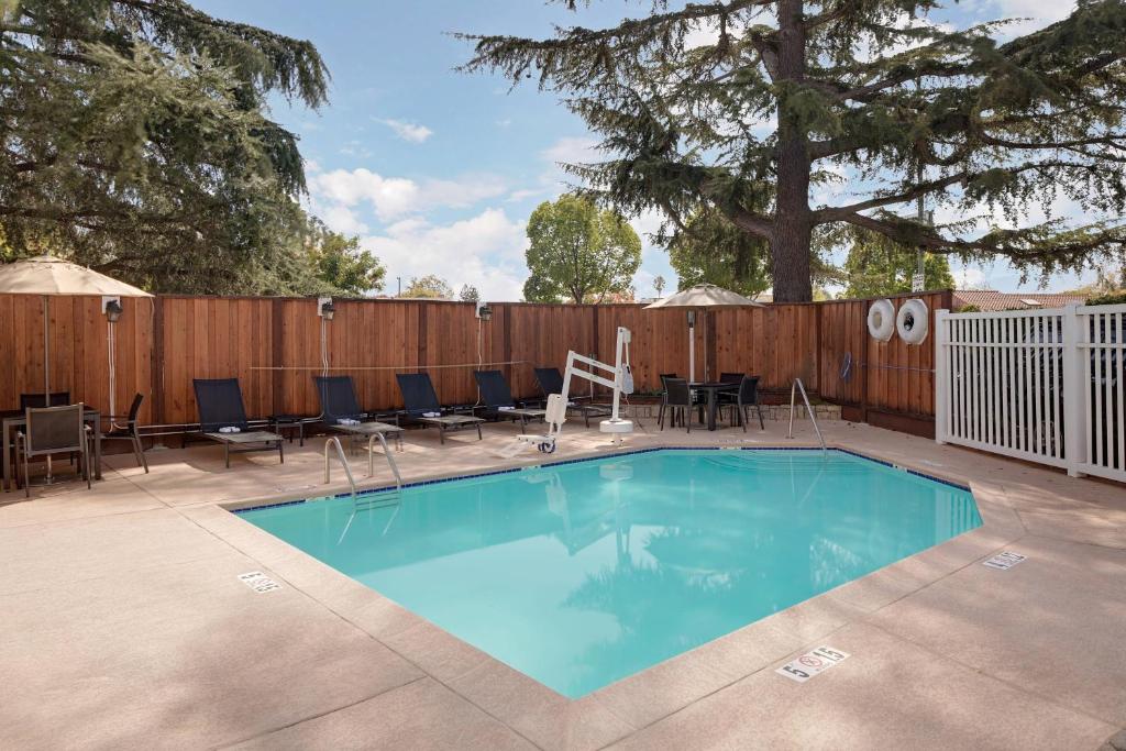 una piscina con sillas y una valla de madera en Residence Inn San Jose Campbell, en Campbell