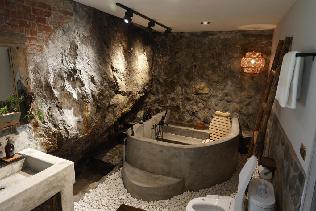 a stone bathroom with a tub and a sink at 濦崌四季 Lermite 金瓜石包棟民宿2-8人 in Ruifang
