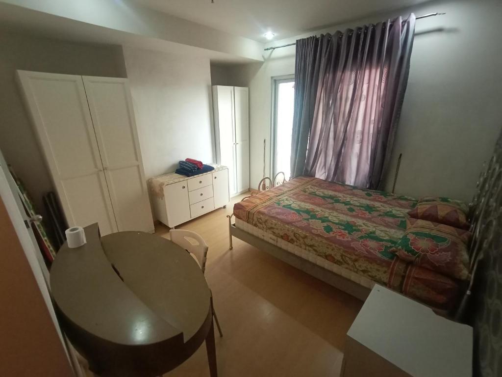 a bedroom with a bed and a table and a window at Apartment Thamrin City 1 Bedroom near Tanah Abang in Jakarta