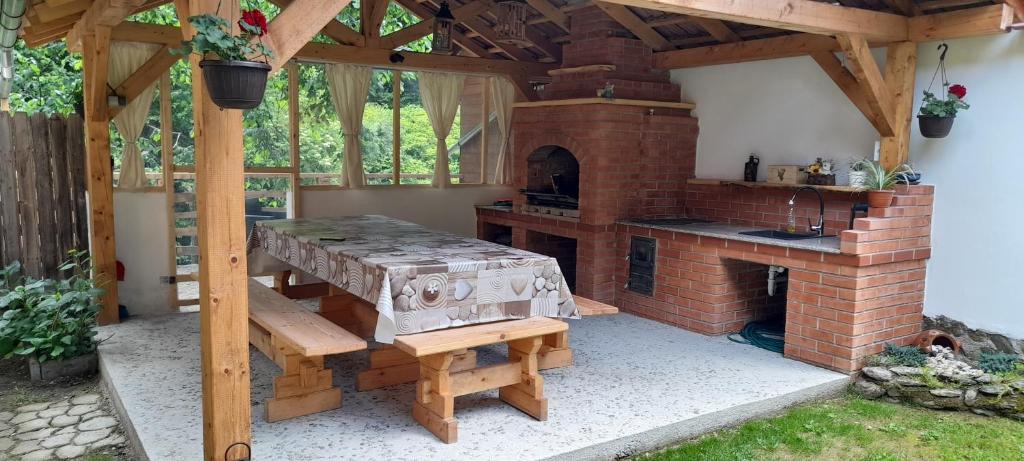 an outdoor kitchen with a brick fireplace and a table at Casa Iulia & Matei in Cârțișoara