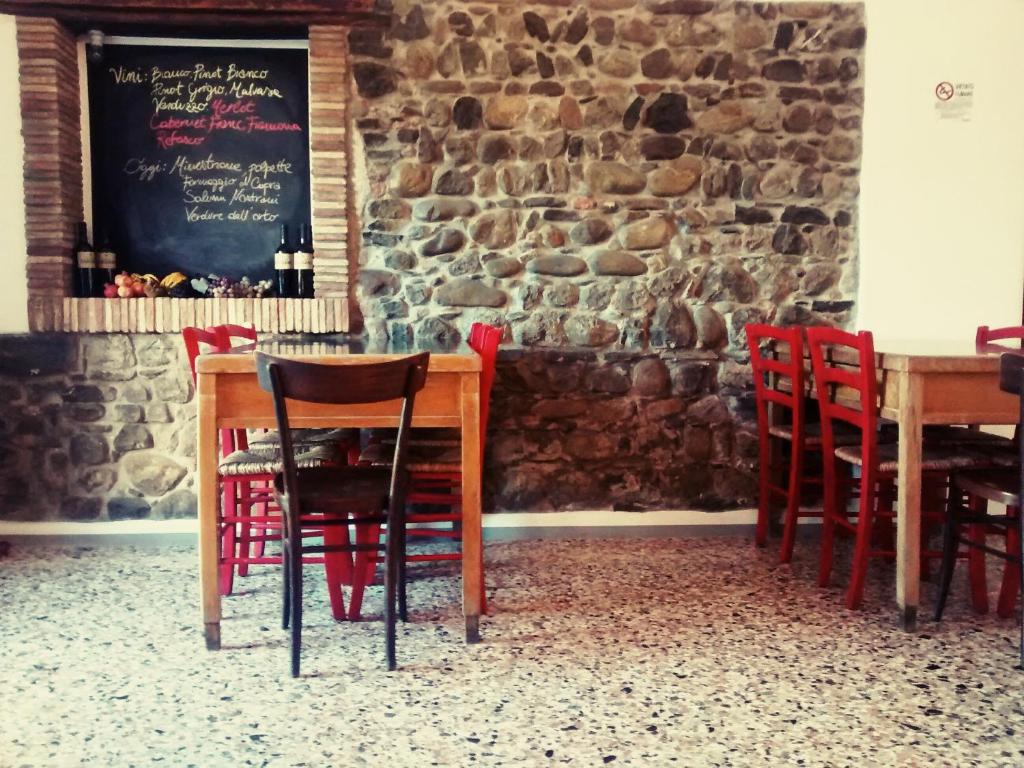 a dining room with red chairs and a stone wall at Agriturismo Scribano in Prepotto