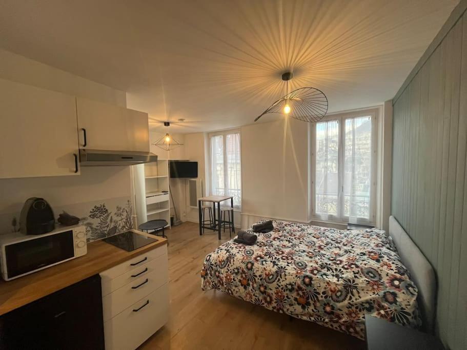 Il comprend une chambre avec un lit et une cuisine équipée d'un four micro-ondes. dans l'établissement Appartement de charme dans le residence historique du Grand hotel, à Aix-les-Bains