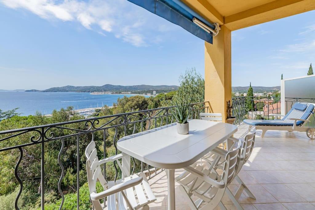 une table blanche et des chaises sur un balcon dans l'établissement Le Manon, vue imprenable sur la baie du Lavandou, au Lavandou