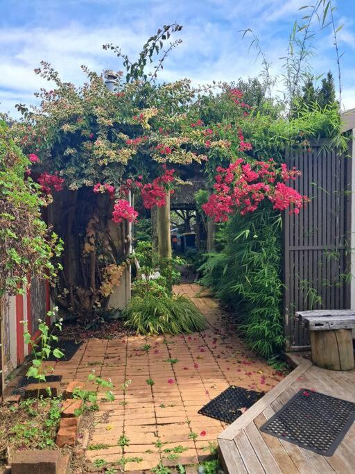 a garden with pink flowers and a fence at Manukorihi Secret Cottage in Waitara