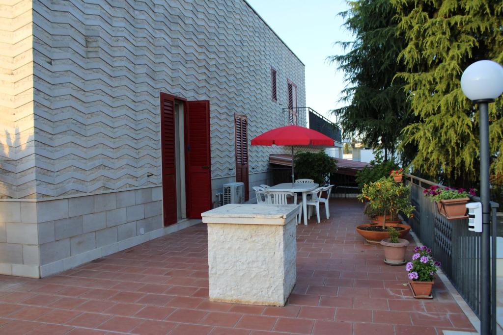 eine Terrasse mit einem Tisch und einem roten Regenschirm in der Unterkunft Villa Rosanna's Haven-Relax a pochi minuti da Monopoli in Antonelli