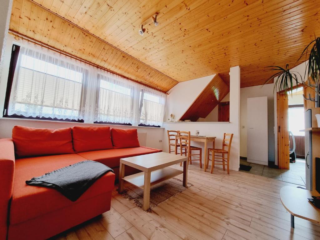 a living room with a red couch and a table at Pension & Wirtshaus ''Tun Eikkoter'' Eichkater in Wieck