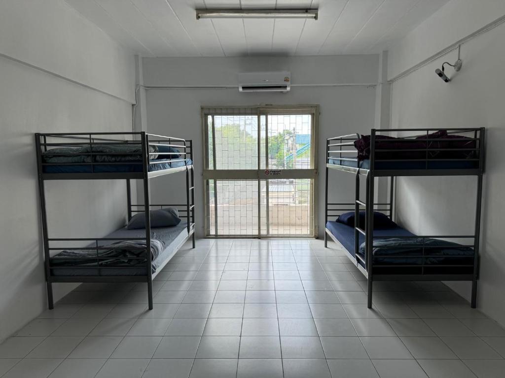 3 stapelbedden in een kamer met een raam bij JS786 Hostel in Pattaya