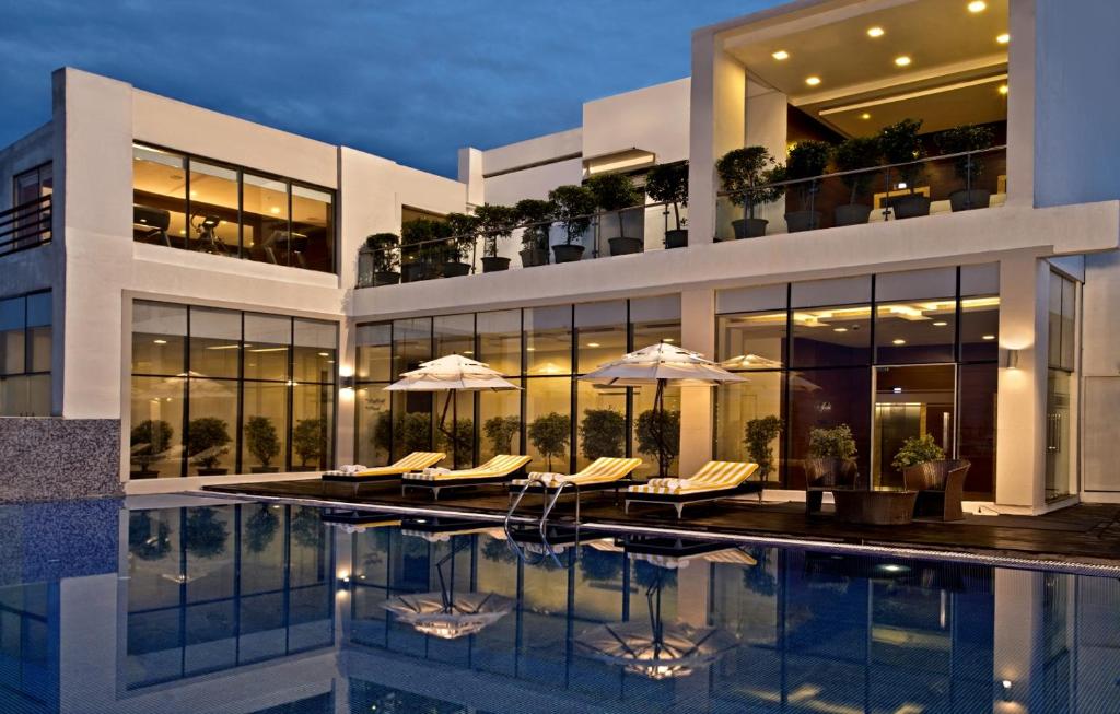 a building with a swimming pool with chairs and umbrellas at Golden Tulip Lucknow in Lucknow