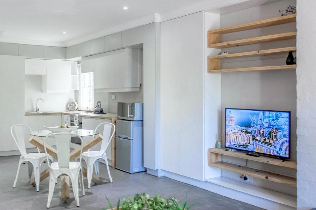 a kitchen and dining room with a table and a tv at Sandton Cozy Apartment in Johannesburg