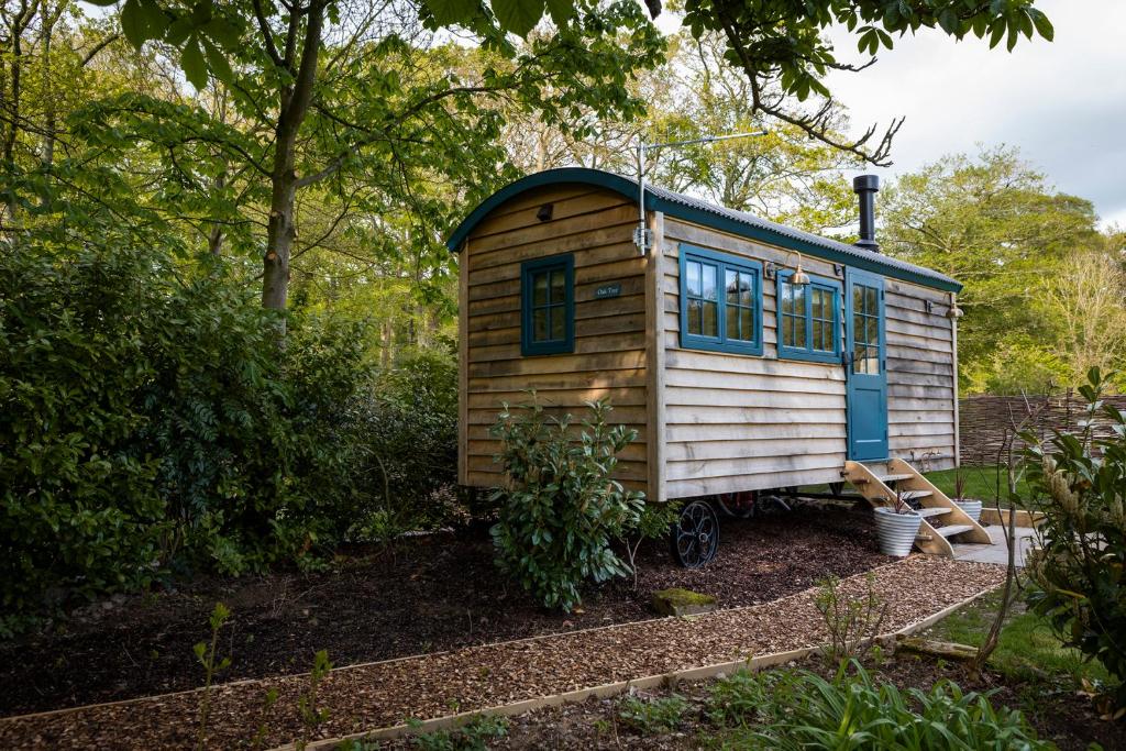 a tiny house is sitting in a garden at Oak Tree Shepherds Hut Chatsworth Estate in Baslow