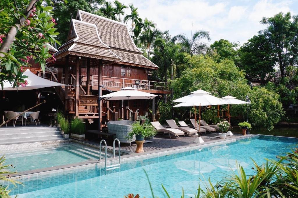 a resort with a swimming pool and a house at Baansuwanburi - บ้านสุวรรณบุรี in Chiang Mai