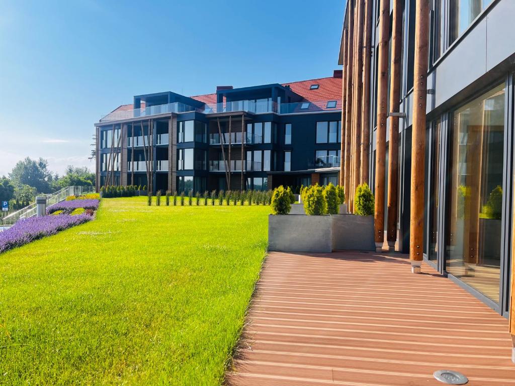 a building with a green lawn next to a building at Pratum Pink&Blue Mikołajki - Apartament 37 Stone&Wood in Mikołajki
