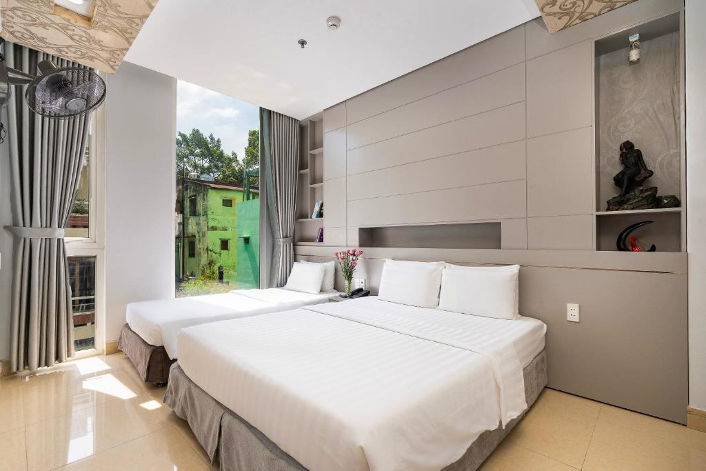 2 Betten in einem Hotelzimmer mit Fenster in der Unterkunft Lucky Star Hotel Q5 in Ho-Chi-Minh-Stadt