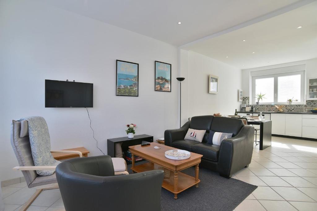 un salon avec un canapé, des chaises et une télévision dans l'établissement Les Myosotis du Val - Duplex à quelques pas de la mer, à Pléneuf-Val-André