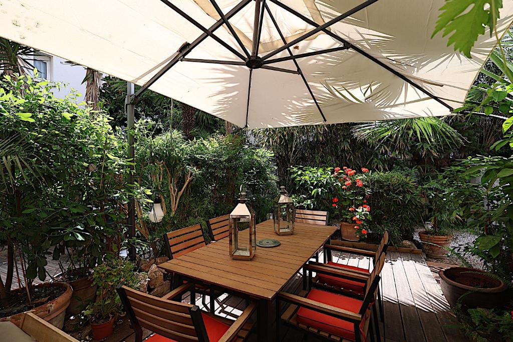 - une table en bois avec des chaises et un parasol dans le jardin dans l'établissement Appartement L'Etang Cannes Pointe Croisette, à Cannes
