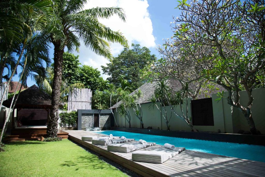 a pool with chaise lounges and a row ofvisorvisor at Downtown Villas in Seminyak