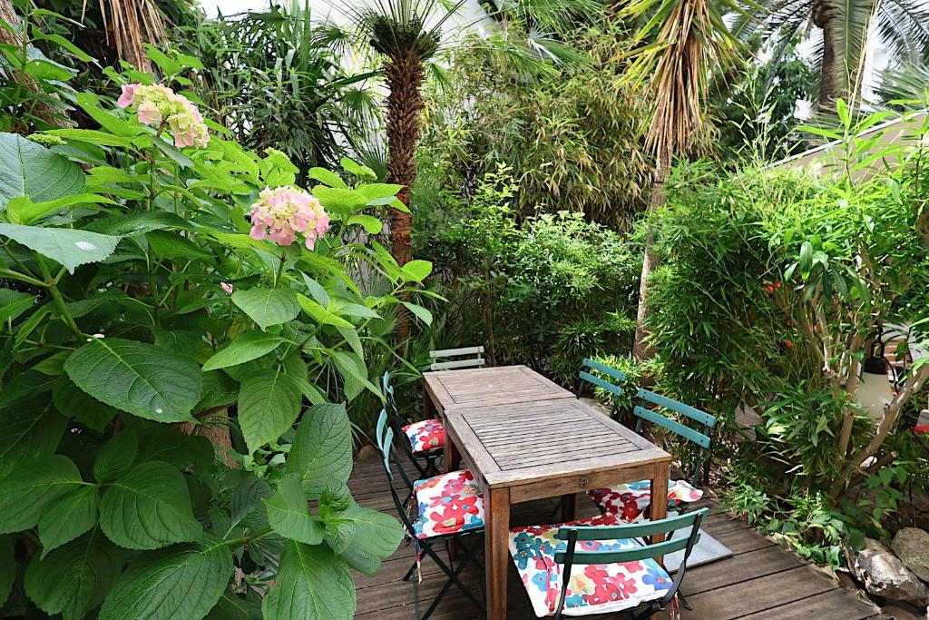 - une table et des chaises en bois dans le jardin dans l'établissement Les Fleurs, à Cannes