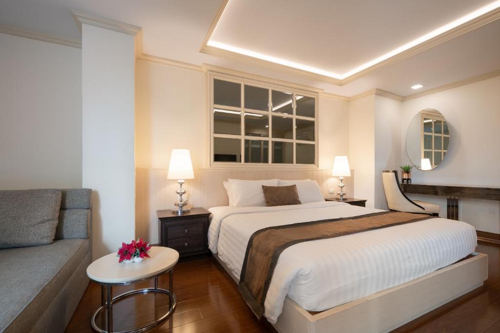 a bedroom with a large bed and a couch at Syama Hana Executive Apartments Thonglor in Bangkok