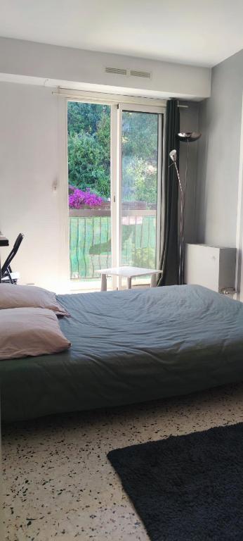 une chambre avec un grand lit et une grande fenêtre dans l'établissement F1 - 8MIN DE LA PLAGE - 5MIN TRAMWAY, à Nice