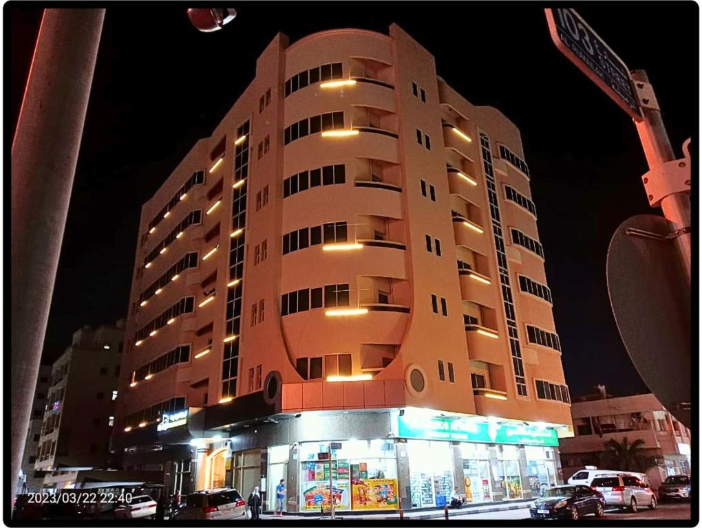 AL MARJAN FURNISHED APARTMENTS في عجمان: مبنى طويل أمامه متجر