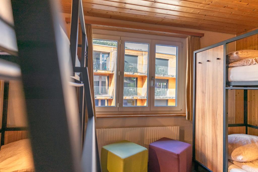 a small room with a window and two stools at Eiger Lodge Easy in Grindelwald