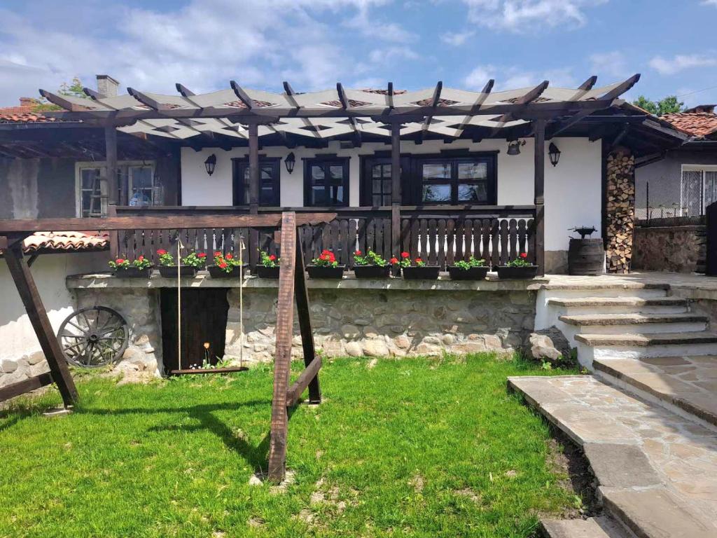 a house with a wooden pergola on a yard at Къща за гости -Абаджиевата къща in Kotel