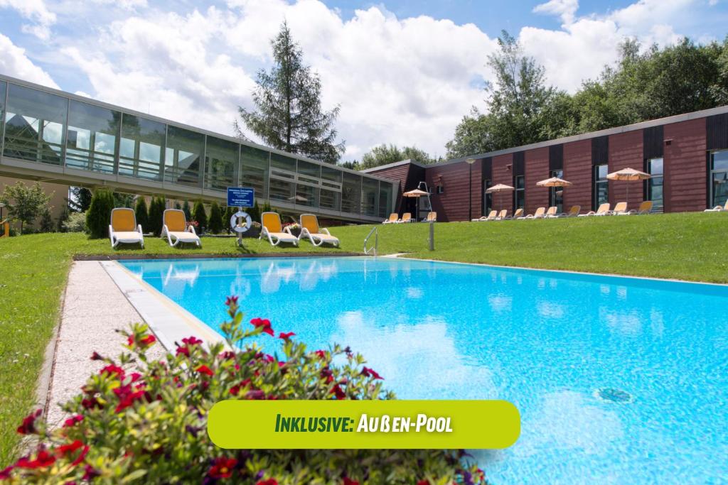 a swimming pool in front of a building at AHORN Waldhotel Altenberg in Kurort Altenberg