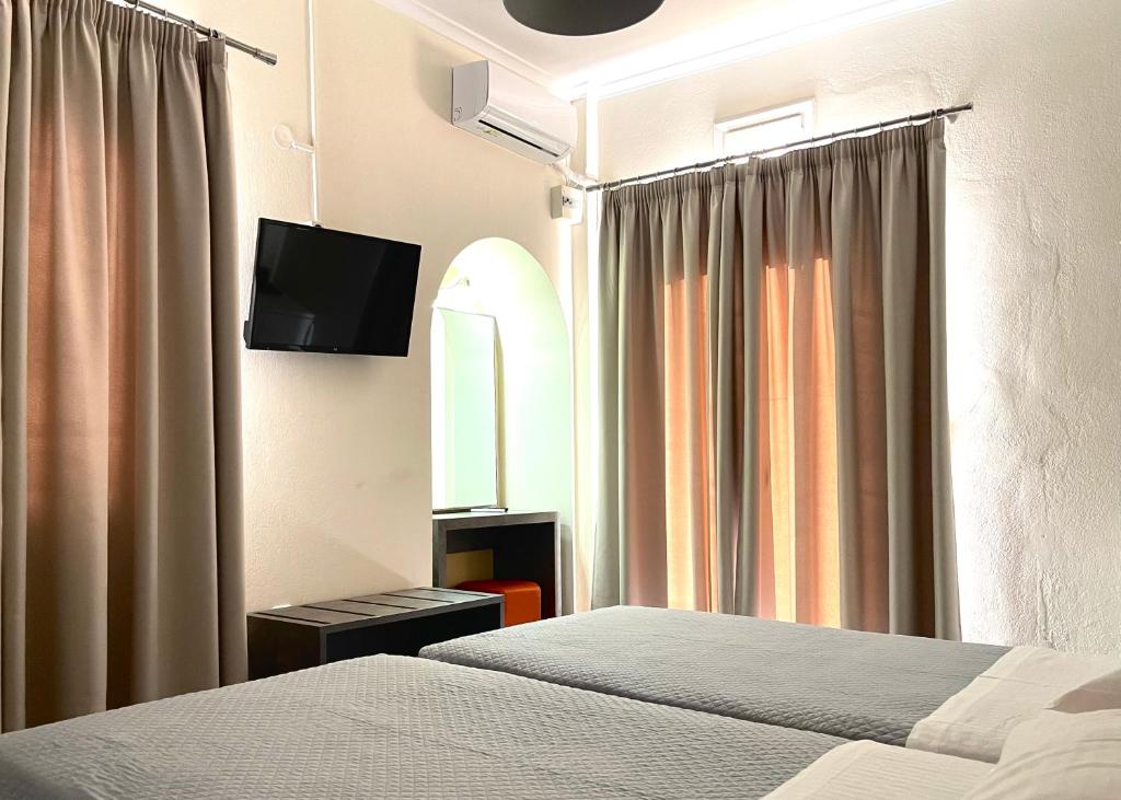 a hotel room with two beds and a flat screen tv at Albatros Hotel in Karterados