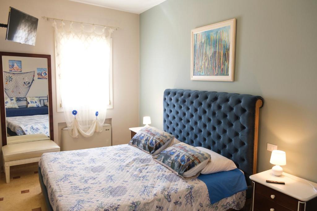 een slaapkamer met een bed met een blauw hoofdeinde en een raam bij Suite Blue Laguna in Chioggia