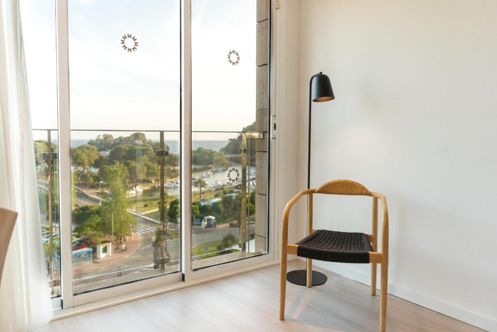 a chair in a room with a large window at Minura Cala Galdana & Apartamentos d'Aljandar in Cala Galdana
