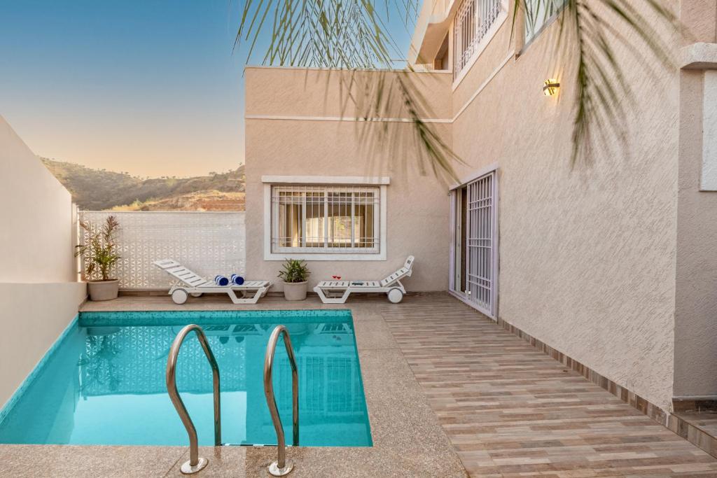 a swimming pool in the backyard of a house at ELIVAAS Shourya Zenna Luxe 3BHK Villa with Pvt Pool, Udaipur in Udaipur