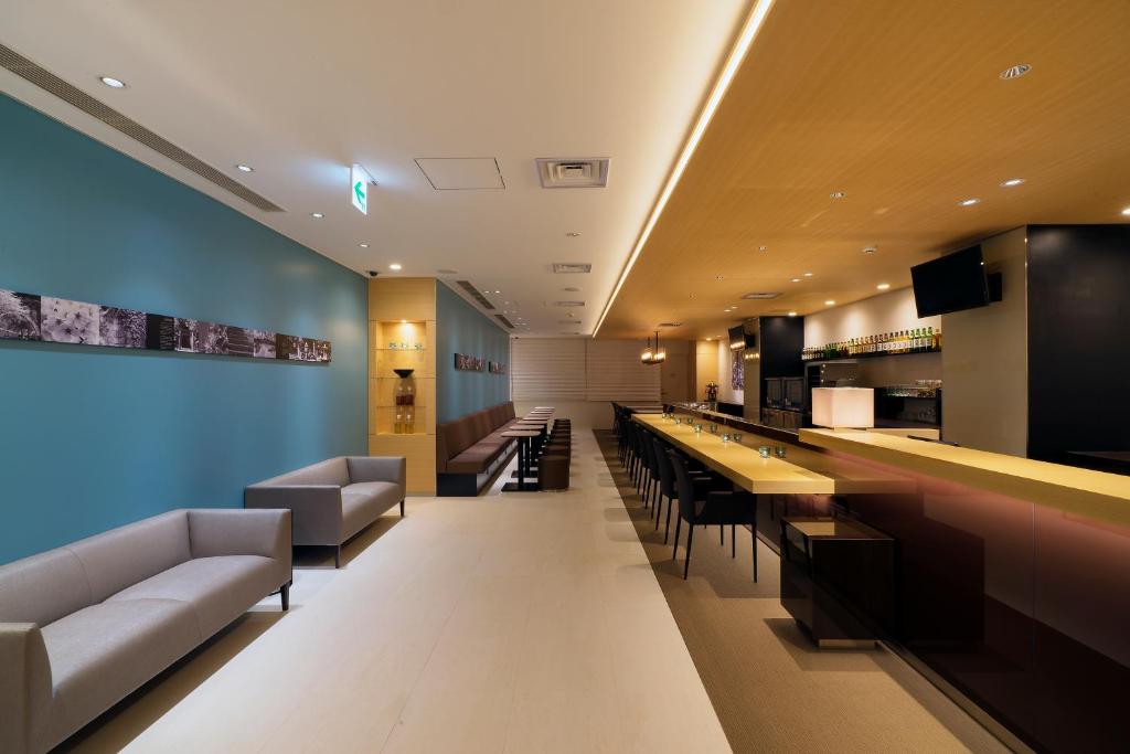 a restaurant with a bar with couches and a counter at First Cabin Shinbashi Atagoyama in Tokyo