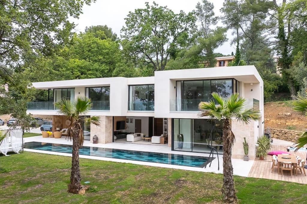une maison avec une piscine et des palmiers dans l'établissement Luxueuse Villa californienne à Opio, à Opio