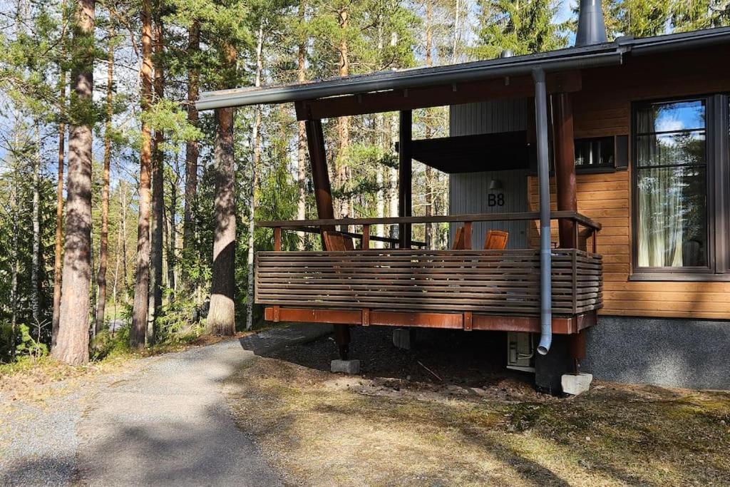 a house with a porch on the side of a forest at Kylpyla Spa, Saimaa Villa Efrat B8 in Imatra