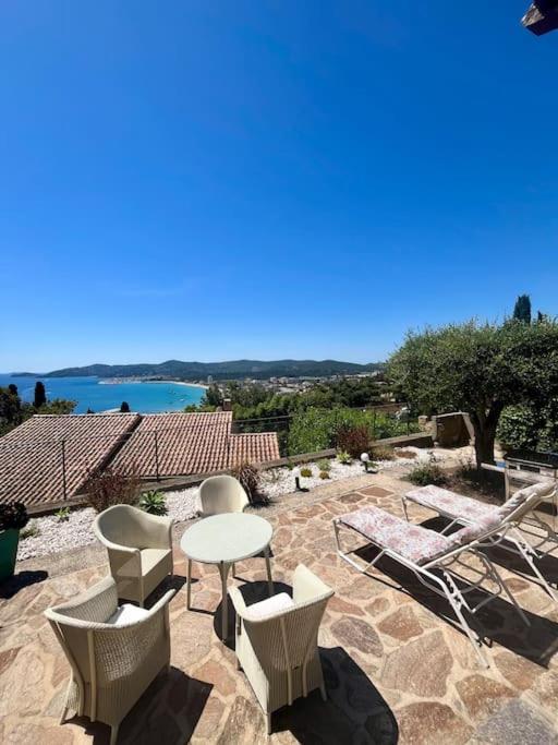 d'une terrasse avec des chaises et une table et une vue sur l'eau. dans l'établissement Villa paisible vue panoramique, au Lavandou