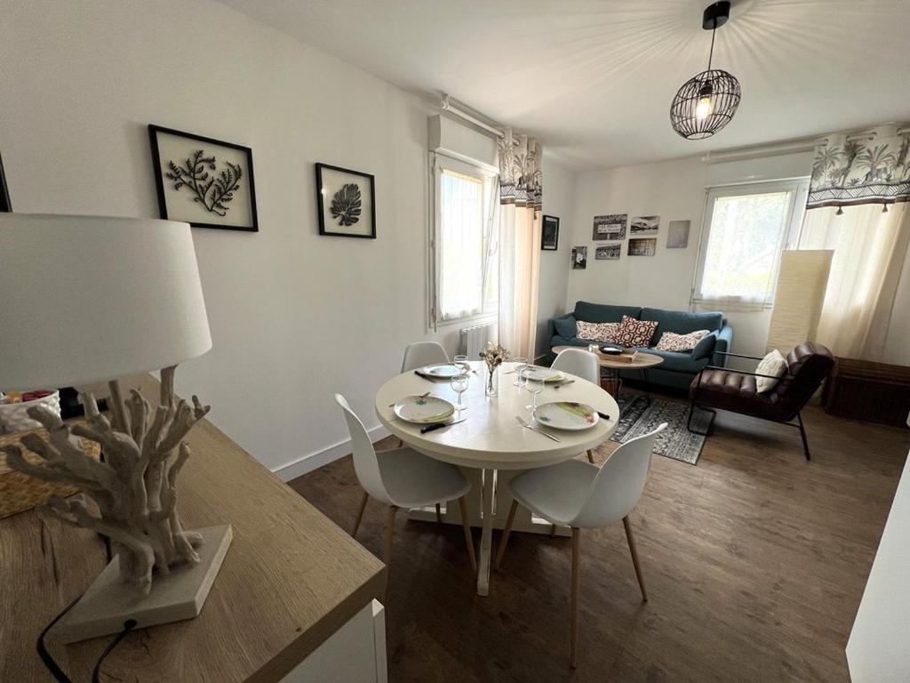 un salon avec une table et des chaises blanches dans l'établissement Appartement 4 pers Quartier de l'Isle - Saint Cast, à LʼIsle-Saint-Cast